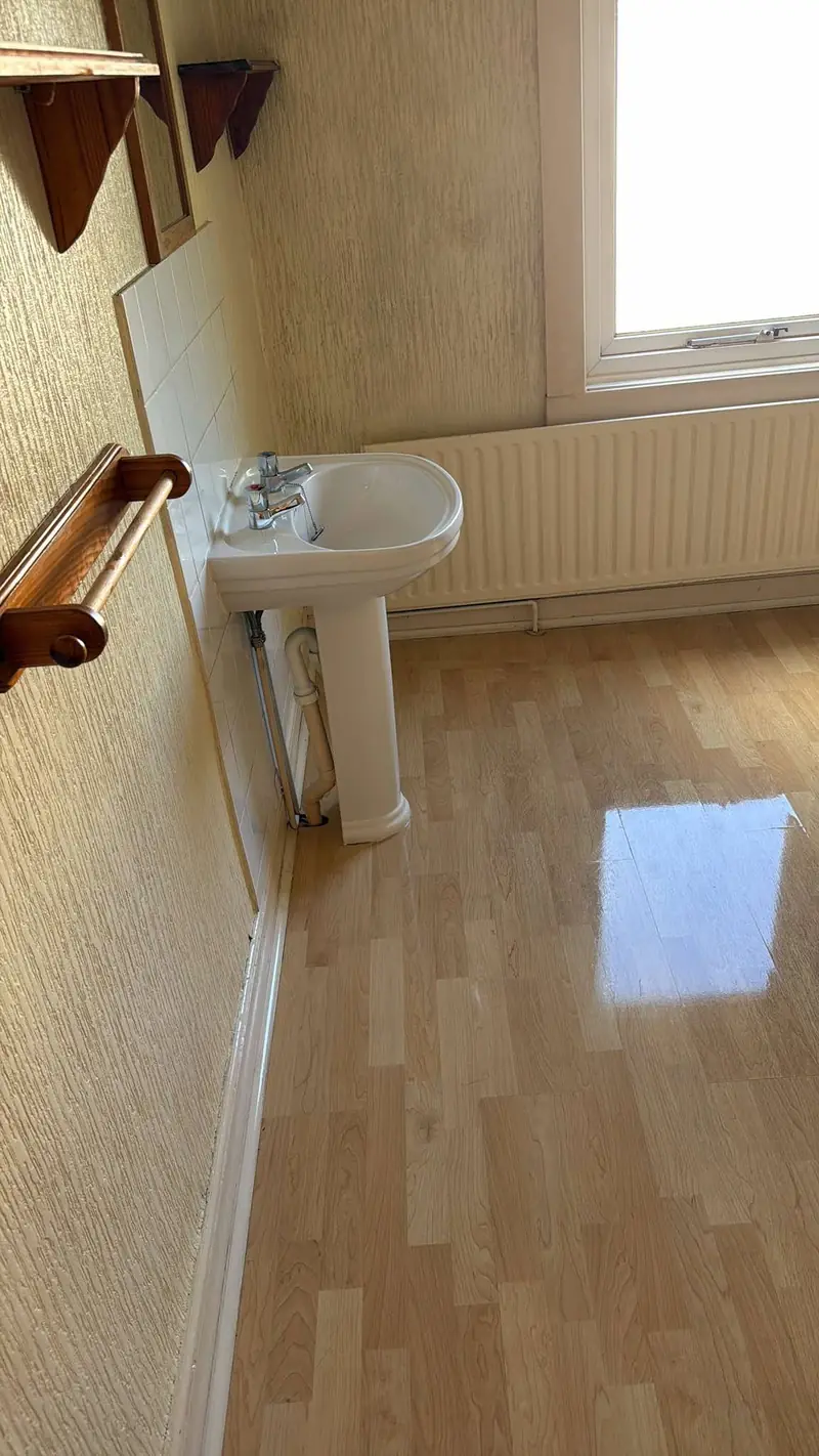 Pedestal basin and glossy laminate floor in a bright bathroom