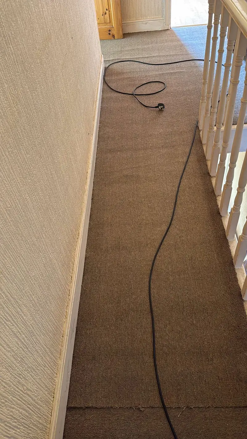 Upstairs landing carpet with a cable on the floor and white banister