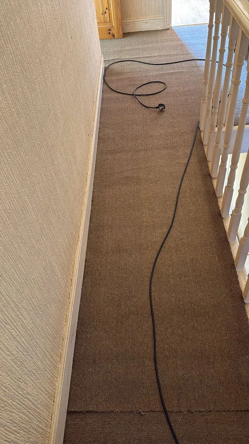Brown carpet along an upstairs landing beside the banister