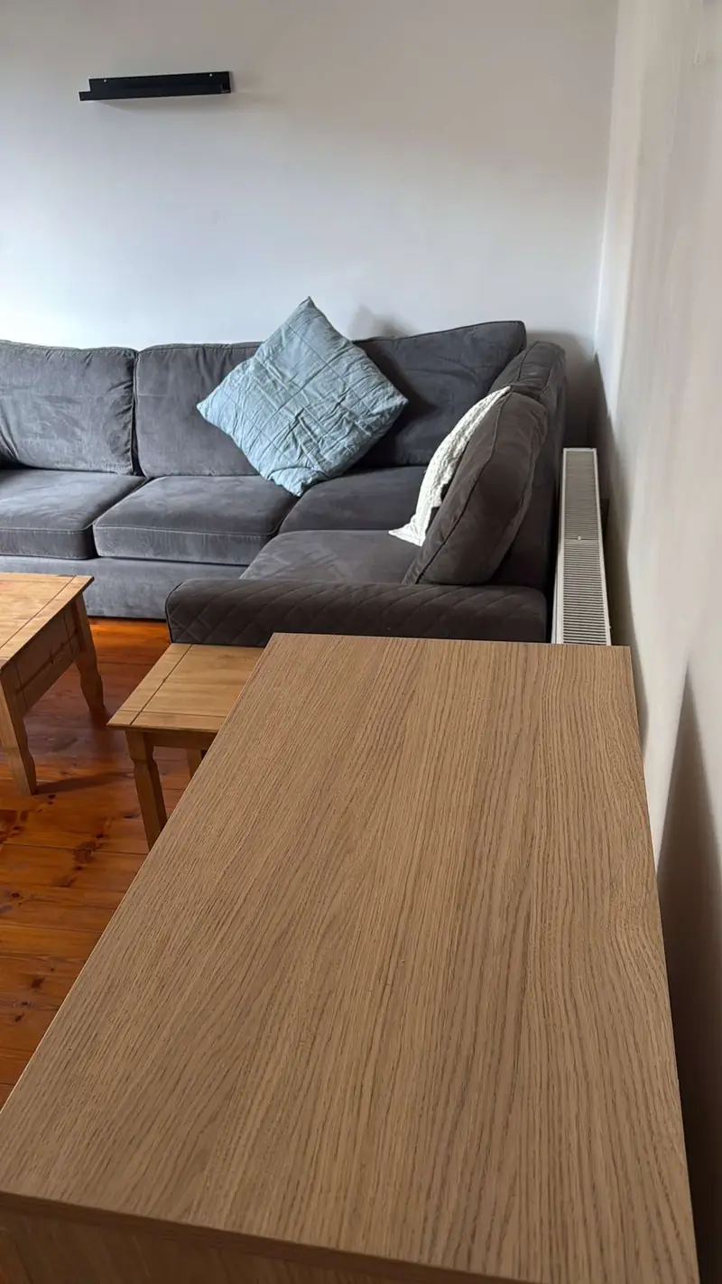 Living room with a grey corner sofa, wooden tables and pine floorboards