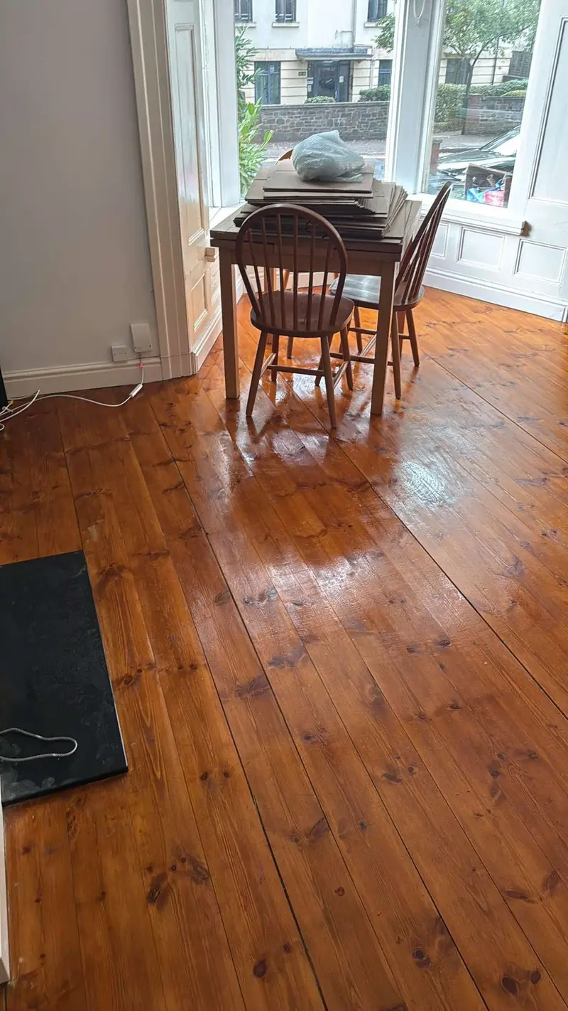 Glossy wooden floorboards around a dining table in a bay window